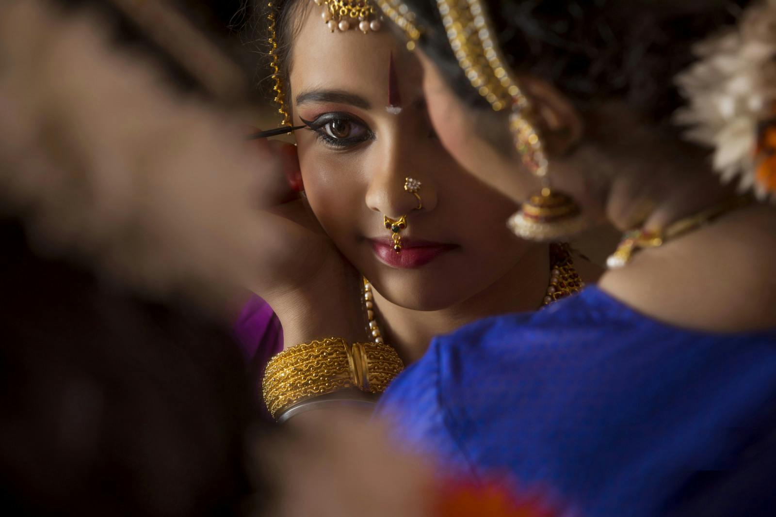 Bharatanatyam dancer applying kajal in her student’s eyes (Getty)
