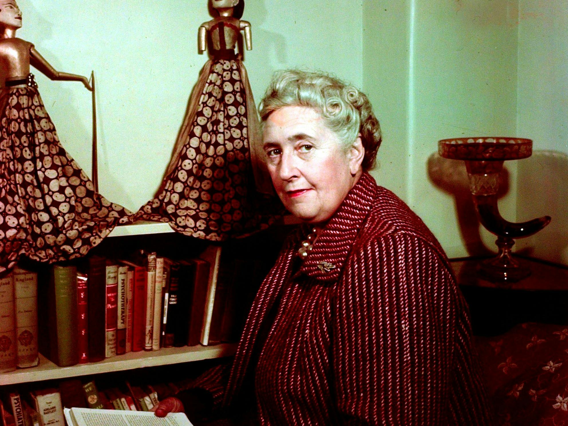 English writer Agatha Christie (1890-1976) seated reading by a bookshelf of books in a living room at her home, Winterbrook House near Wallingford, Oxfordshire in 1949 (Popperfoto via Getty Images)