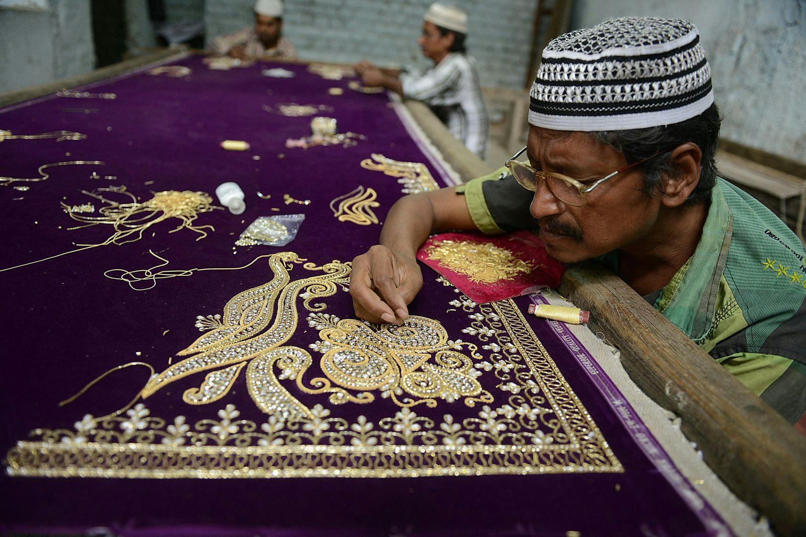 Workers perform custom ‘zardozi’ embroidery work on a saree in 2014 (Noah Seelam/AFP, Getty Images)