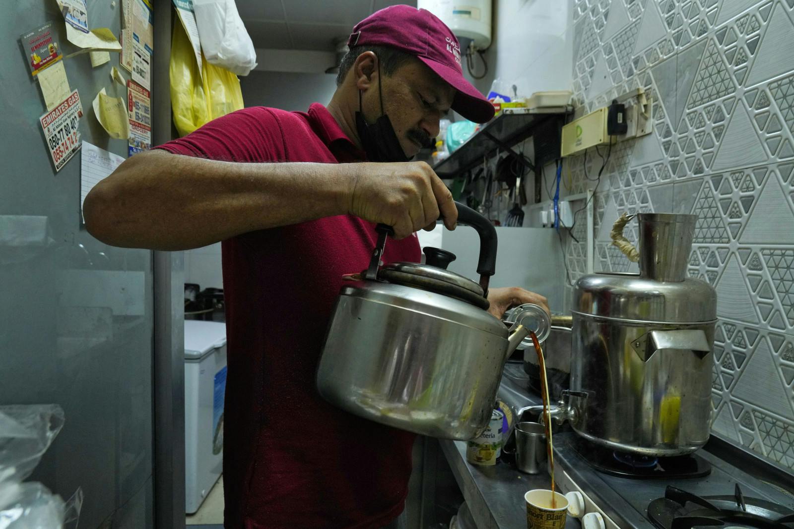 An Indian tea seller, Rafik, pours karak chai in Dubai, U.A.E., Aug. 24, 2022. Inflation has increased prices, a blow to migrant workers who depend on the drink (AP Photo/Jon Gambrell)