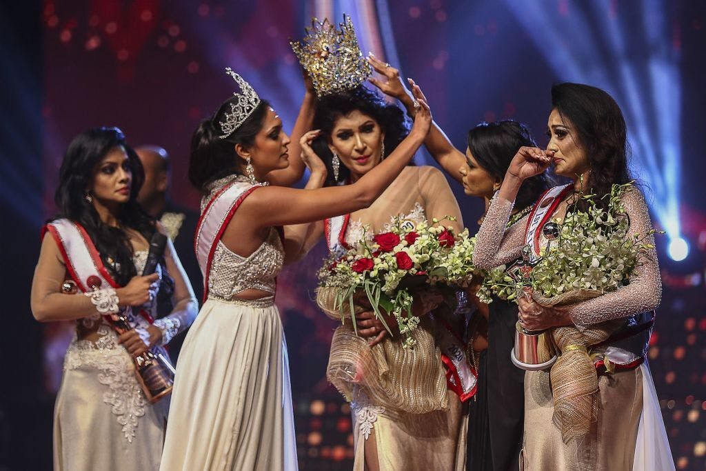 Caroline Jurie removes the crown of 2021 winner Pushpika de Silva, as she is disqualified over the accusation of being divorced, at a beauty pageant for married women in Colombo (Photo by AFP via Getty Images)