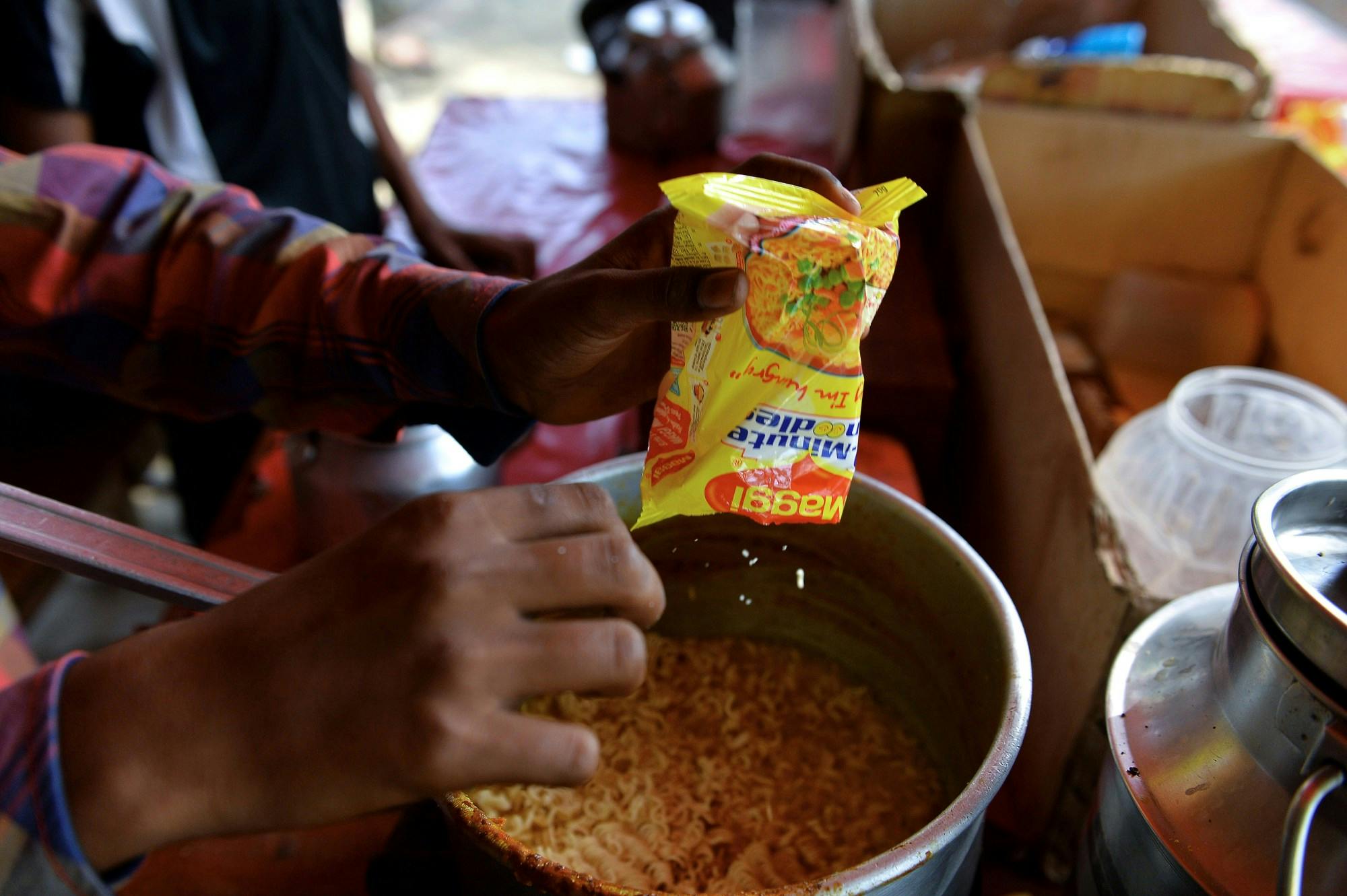 An Indian youth prepares Nestle Maggi instant noodles at his makeshift roadside food stall on the outskirts of New Delhi on June 3, 2015. (Chandan Khanna/AFP via Getty Images)
