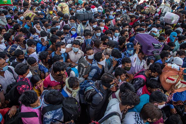 Indian migrant workers and labourers along with their families stuck in the national capital, with and without protective masks crowd to board buses to return to their native villages (March 29, 2020) (Photo by Yawar Nazir/Getty Images)
